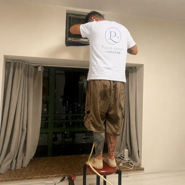 技師站在梯上清洗窗口式冷氣機